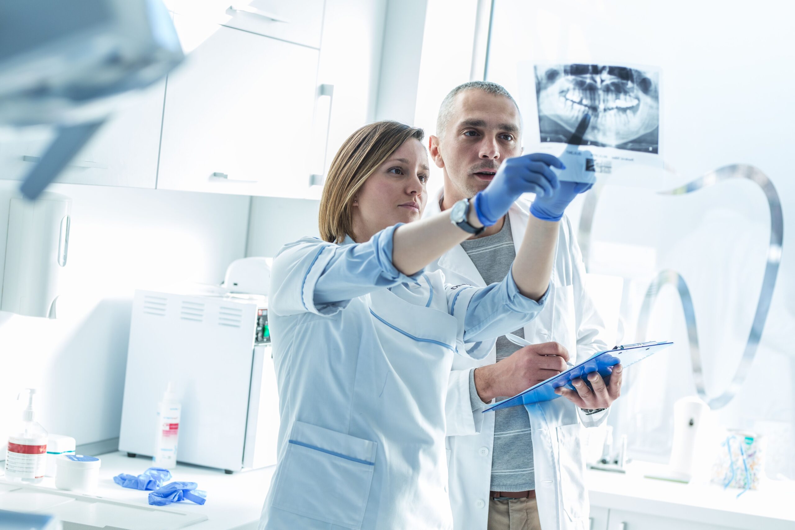 Trusted dental handpiece repair in Fort Worth, TX, supporting professional dentists and their colleagues who highlight teamwork while examining an X-ray to diagnose oral health issues, powered by Optimal Dental Handpiece Repair.